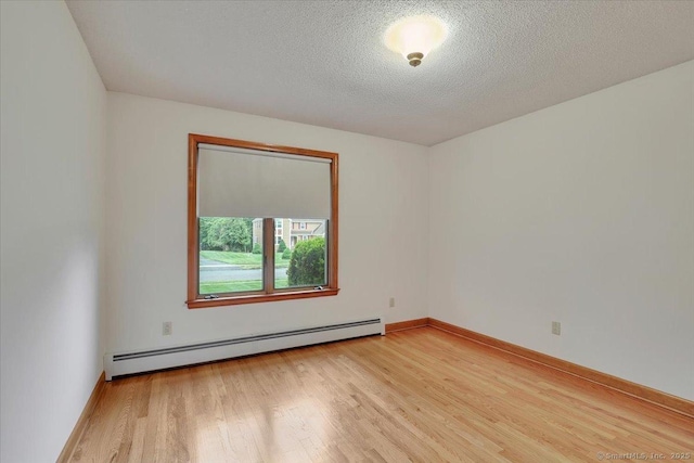 101 Langford Ln, East Hartford, CT 06118 - spare room with a baseboard heating unit, light wood finished floors, a textured ceiling, and baseboards