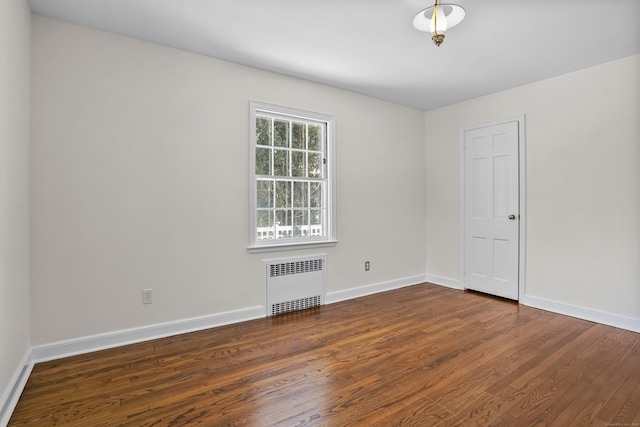 empty room with dark hardwood / wood-style flooring and radiator