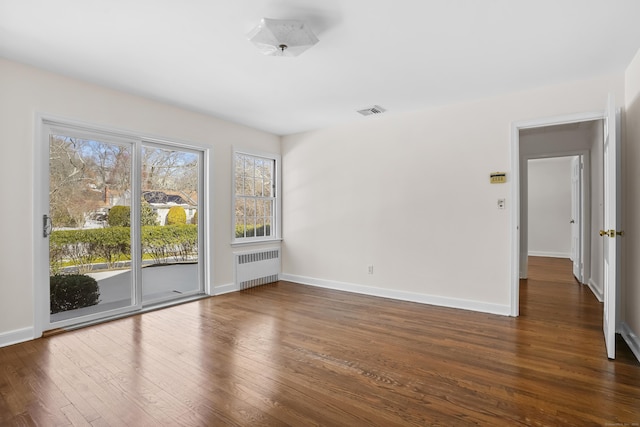 empty room featuring dark hardwood / wood-style floors and radiator heating unit