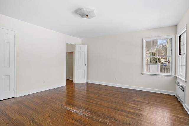 spare room featuring dark hardwood / wood-style flooring and radiator