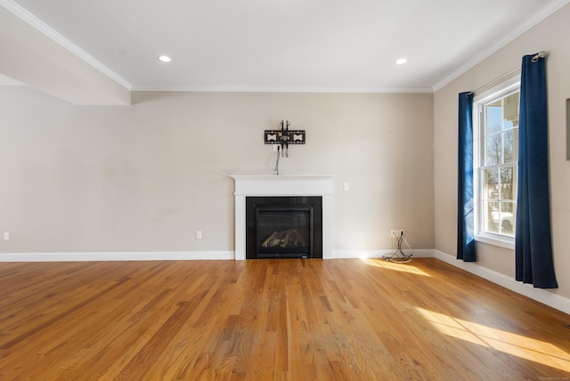 unfurnished living room featuring baseboards, light wood-type flooring, a glass covered fireplace, and crown molding