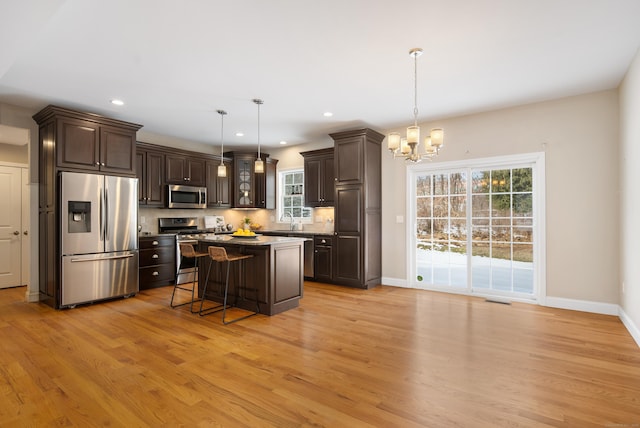 kitchen with dark brown cabinetry, light wood finished floors, visible vents, a breakfast bar area, and stainless steel appliances