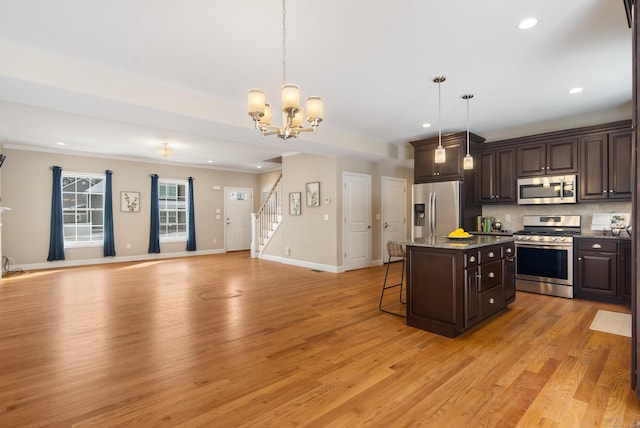 kitchen featuring a breakfast bar area, dark brown cabinetry, stainless steel appliances, backsplash, and a center island