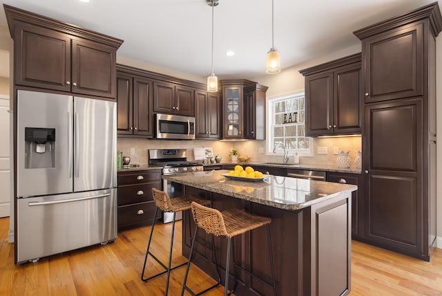 kitchen featuring stainless steel appliances, backsplash, dark brown cabinetry, and light wood-style flooring