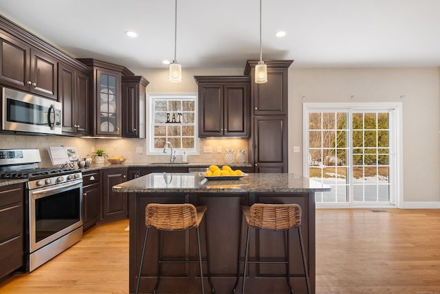 kitchen with stainless steel appliances, a sink, decorative backsplash, and a breakfast bar area