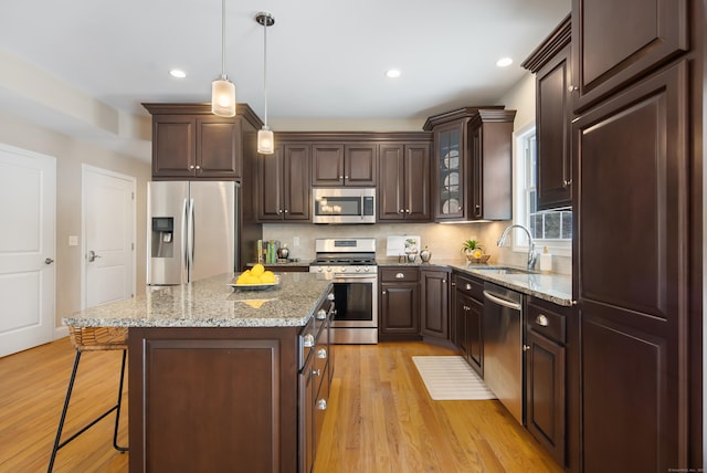 kitchen with stainless steel appliances, light wood-style floors, a sink, and dark brown cabinetry