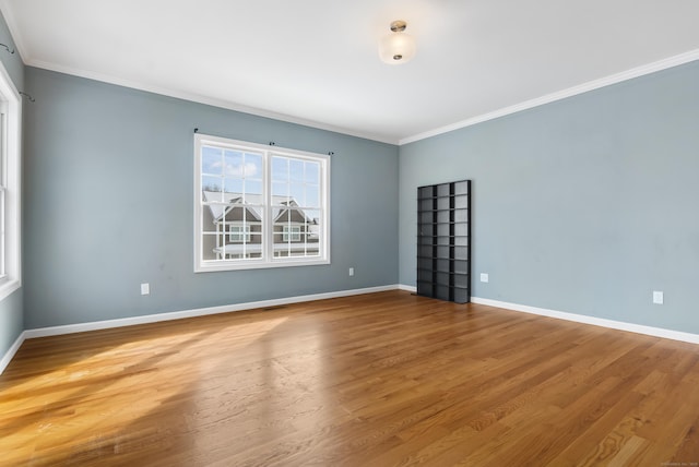 unfurnished room with ornamental molding, wood finished floors, and baseboards