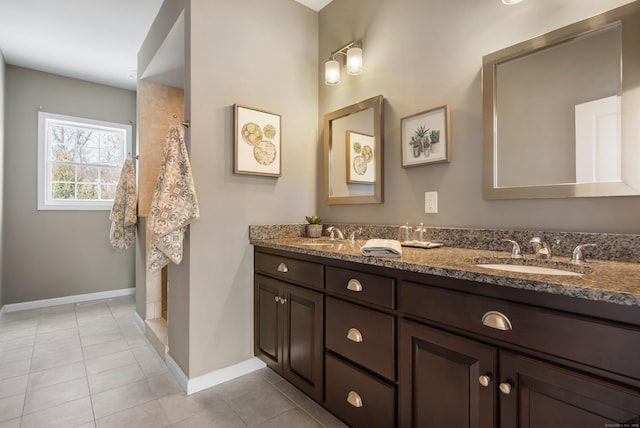 bathroom featuring double vanity, tile patterned flooring, a sink, and baseboards