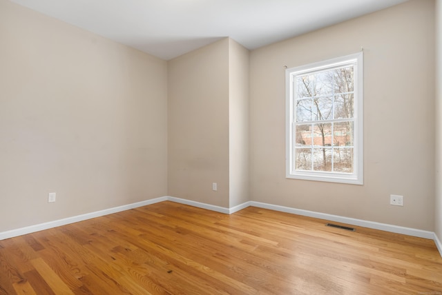 empty room featuring light wood-style flooring, plenty of natural light, and visible vents