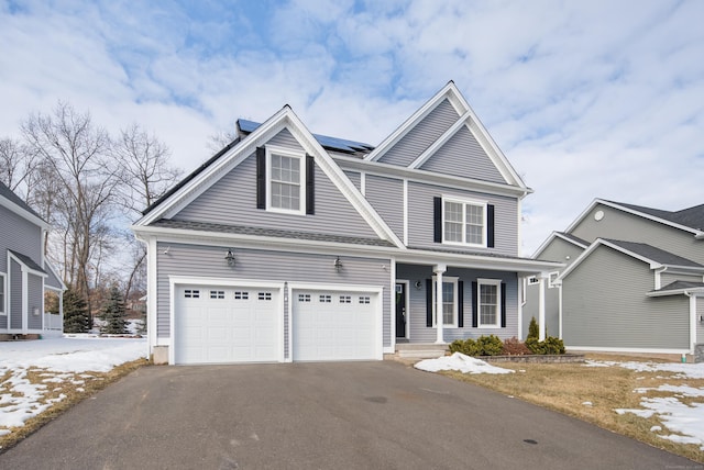 view of front of house with covered porch, solar panels, aphalt driveway, and an attached garage