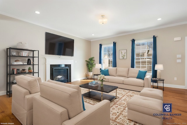 living area with a glass covered fireplace, crown molding, baseboards, and wood finished floors