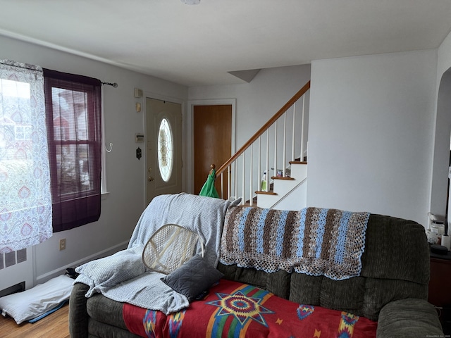 living room featuring wood finished floors, radiator heating unit, and stairway