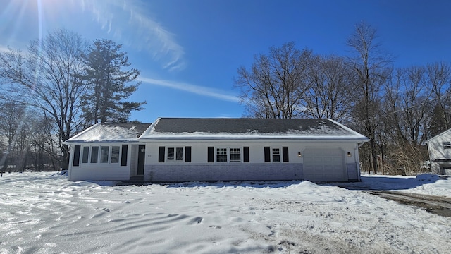 snow covered property with a garage and brick siding