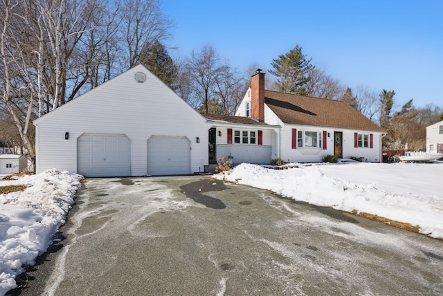 view of front of house featuring an attached garage, a chimney, and aphalt driveway