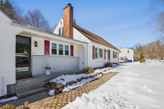 view of front facade with a chimney and brick siding