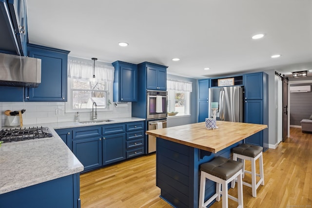 kitchen with blue cabinets, a kitchen island, appliances with stainless steel finishes, and a sink