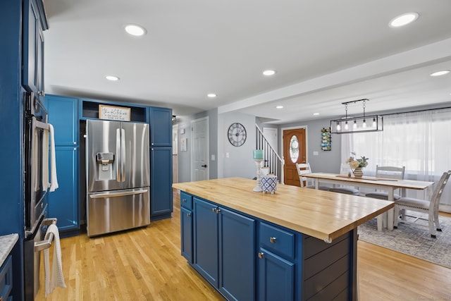 kitchen featuring decorative light fixtures, wooden counters, stainless steel refrigerator with ice dispenser, and blue cabinetry