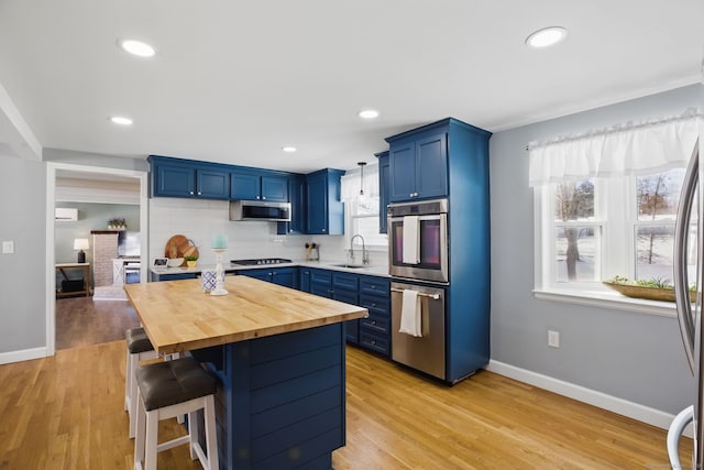 kitchen with blue cabinets, stainless steel appliances, a kitchen island, a kitchen breakfast bar, and wooden counters