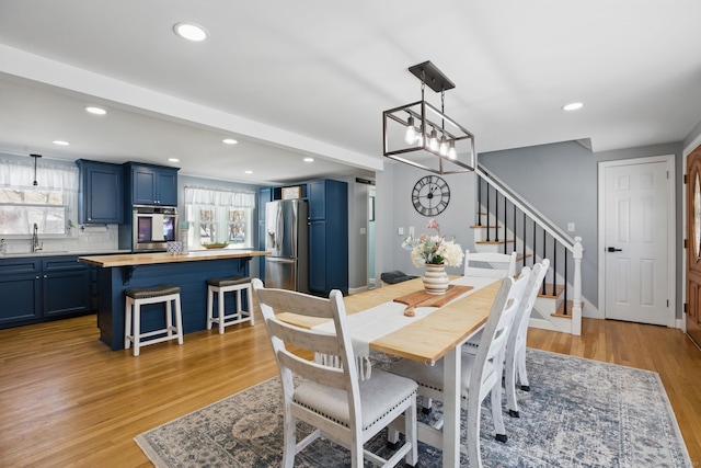 dining space with light wood-style floors, baseboards, stairway, and recessed lighting