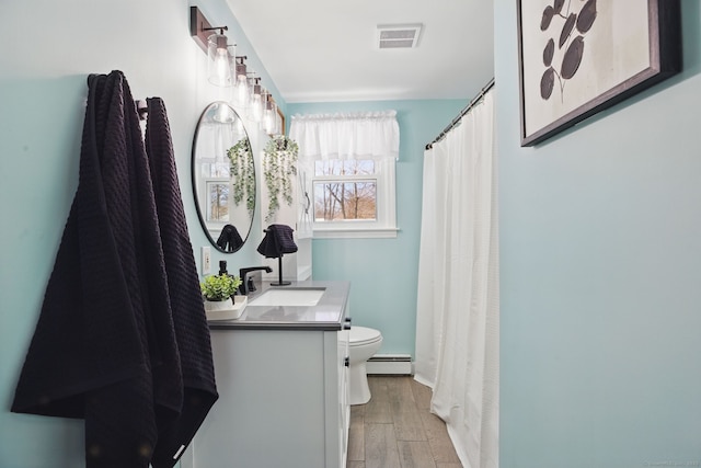 bathroom with a baseboard radiator, visible vents, toilet, vanity, and wood finished floors