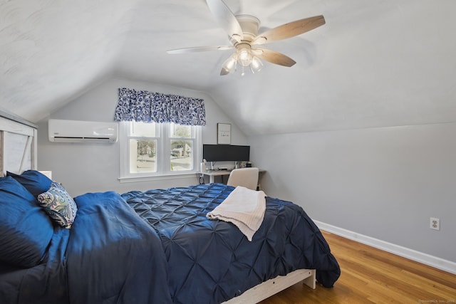 bedroom featuring ceiling fan, wood finished floors, baseboards, vaulted ceiling, and an AC wall unit