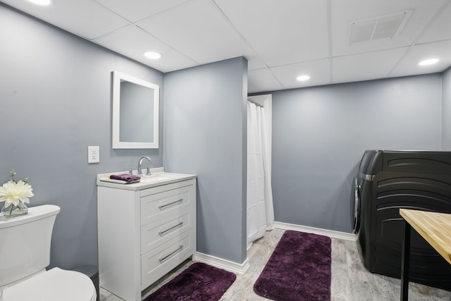 bathroom with washer / dryer, baseboards, visible vents, wood finished floors, and vanity