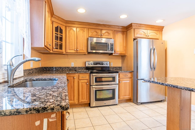 kitchen with glass insert cabinets, stainless steel appliances, a sink, and light tile patterned flooring