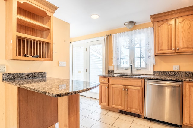 kitchen featuring light tile patterned floors, dark stone countertops, stainless steel dishwasher, open shelves, and a sink