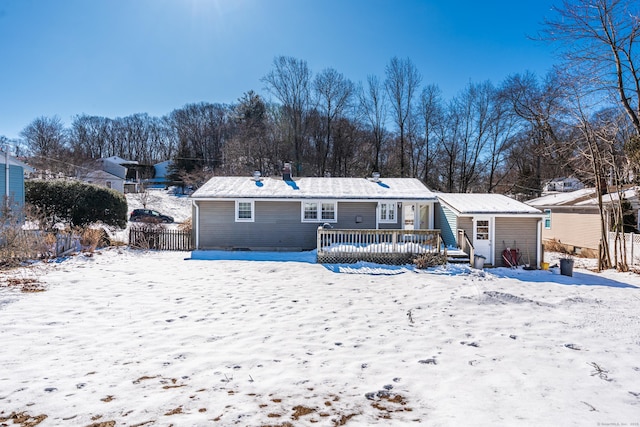 snow covered rear of property with fence and a wooden deck