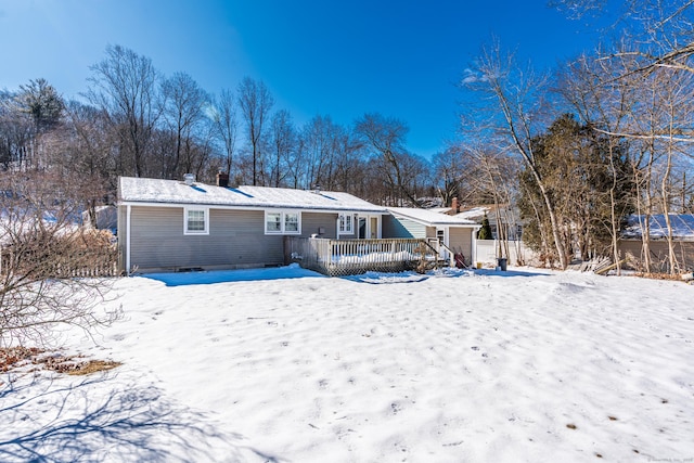 snow covered house featuring a chimney and a deck