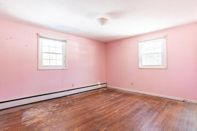 empty room featuring a baseboard heating unit, a wealth of natural light, baseboards, and dark wood-style floors