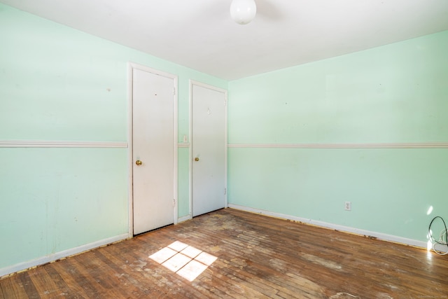 spare room featuring baseboards and dark wood finished floors