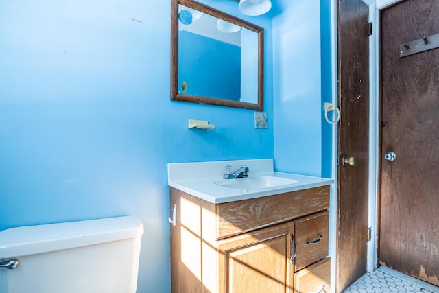 half bath featuring tile patterned flooring, vanity, and toilet