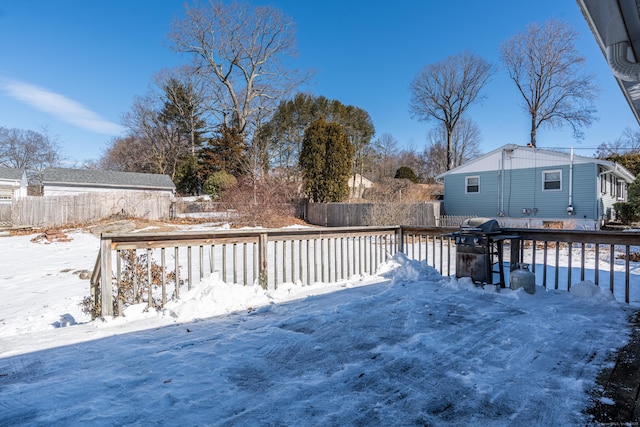 snow covered deck featuring a fenced backyard and area for grilling