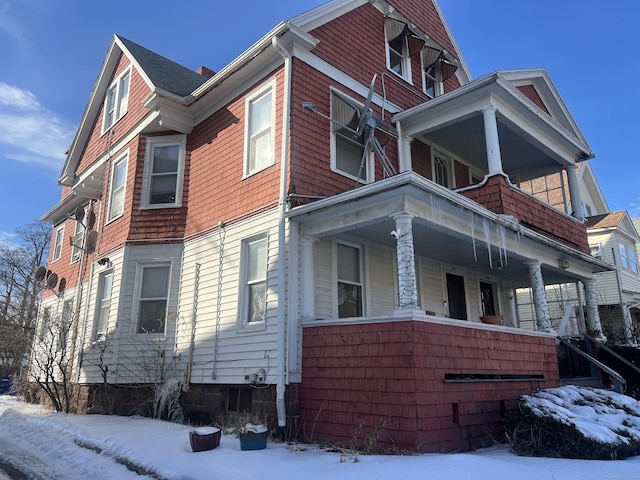 view of snowy exterior featuring a porch and a balcony