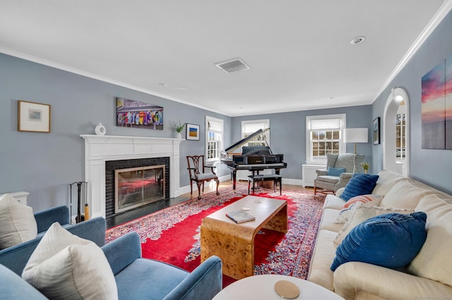 living area with a premium fireplace, wood finished floors, visible vents, and crown molding