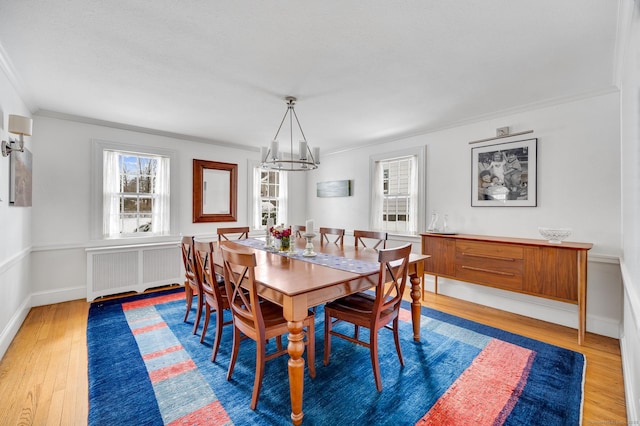 dining area featuring radiator, a healthy amount of sunlight, crown molding, and wood finished floors