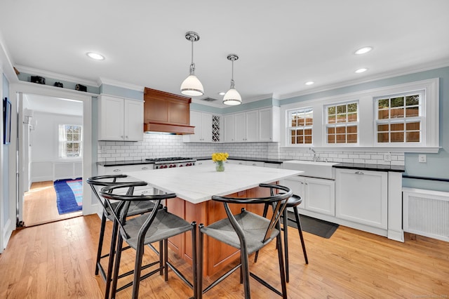 kitchen with radiator heating unit, ornamental molding, a breakfast bar, stove, and a sink