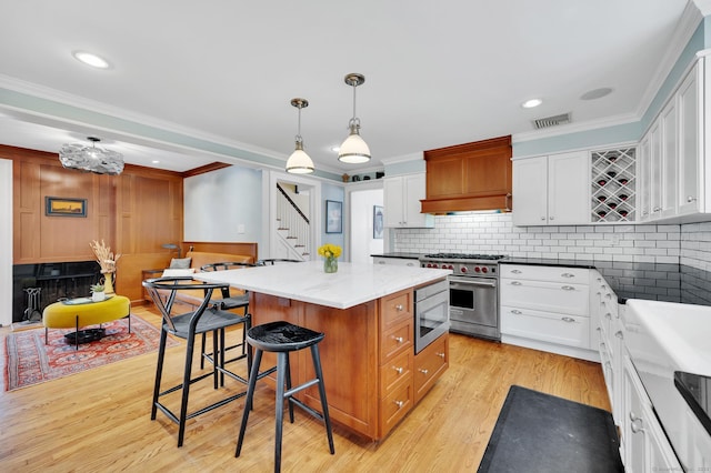 kitchen with visible vents, a kitchen island, a breakfast bar area, custom exhaust hood, and stainless steel appliances