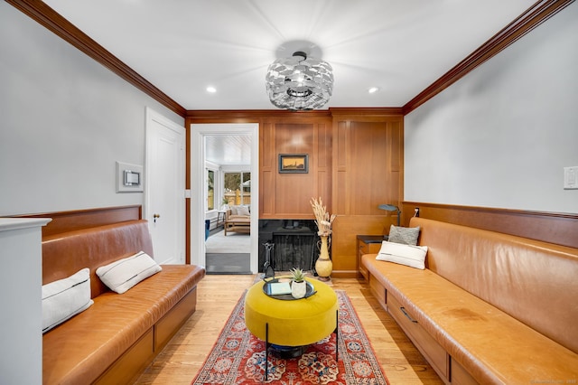 living area with light wood finished floors, a fireplace, and ornamental molding