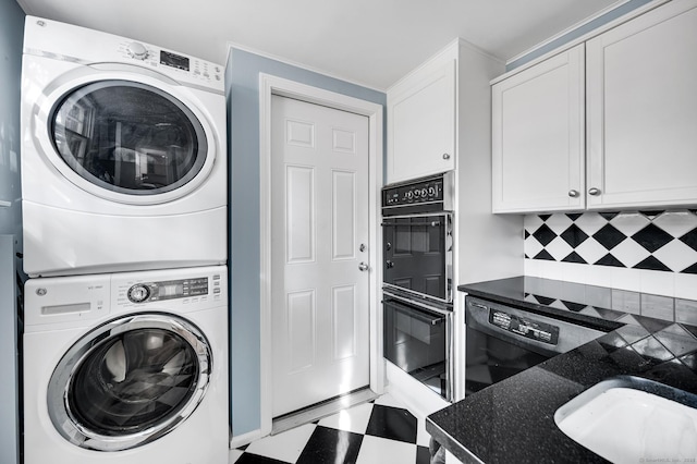 laundry area featuring stacked washing maching and dryer, a sink, and tile patterned floors