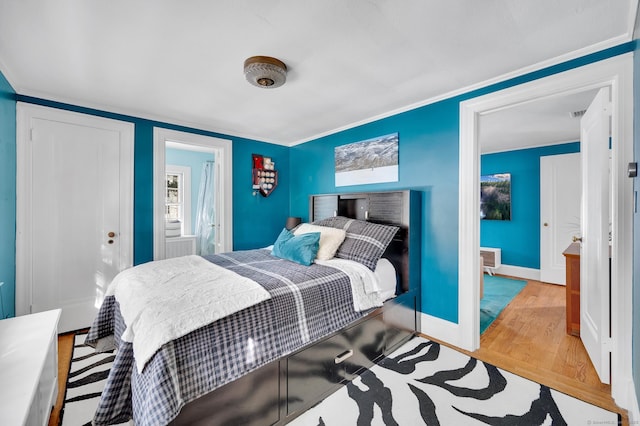 bedroom featuring crown molding, wood finished floors, and baseboards