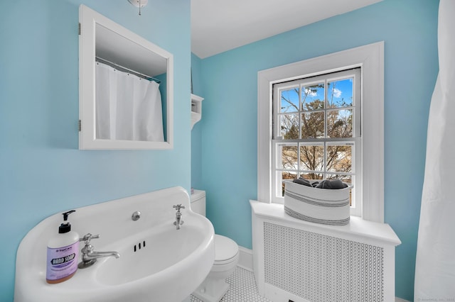 full bath featuring baseboards, toilet, radiator heating unit, tile patterned floors, and a sink