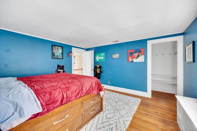 bedroom featuring light wood-type flooring, visible vents, baseboards, and crown molding