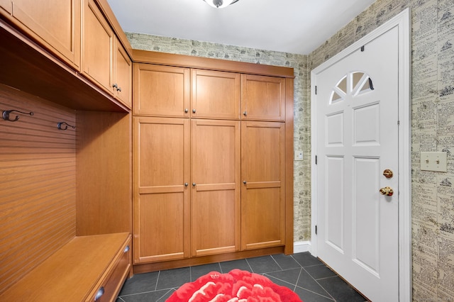 mudroom with dark tile patterned floors and wallpapered walls