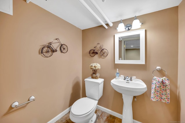 bathroom featuring toilet, baseboards, and a sink