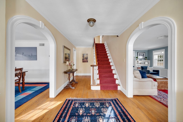 foyer with visible vents, arched walkways, and wood finished floors