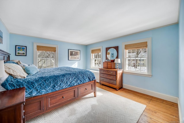 bedroom with crown molding, light wood finished floors, multiple windows, and baseboards