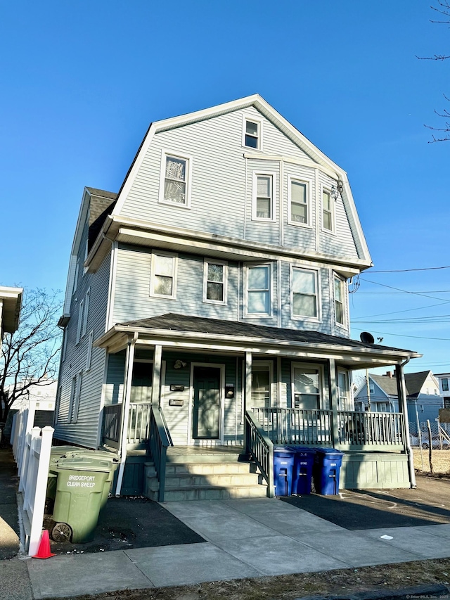 view of front of house with covered porch, a gambrel roof, and a shingled roof