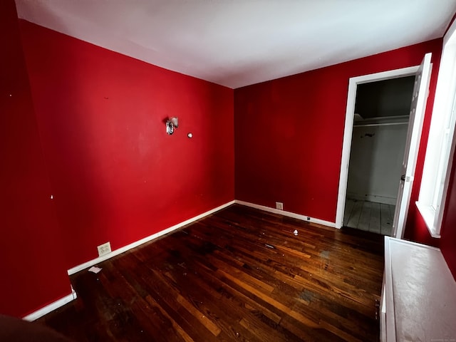 unfurnished bedroom with a closet, dark hardwood / wood-style flooring, and a spacious closet